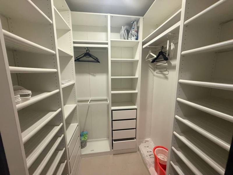 A wardrobe in a 3-room apartment with white shelves and wall hangers.