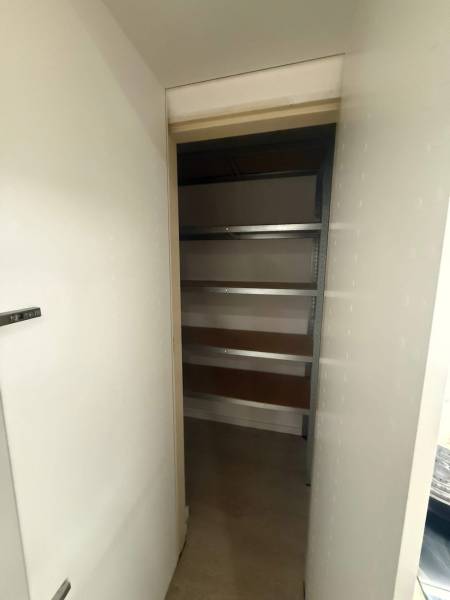 Pantry with shelves inside a 3-room apartment, suitable for storage.