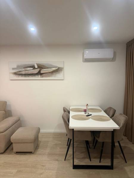 Dining room in a 3-room apartment with a wooden decor floor, table, and chairs.