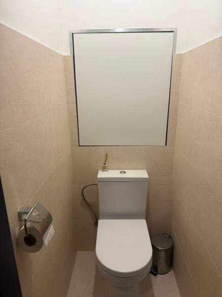 A toilet with beige walls, a mirror, and a bin in a 3-room apartment.
