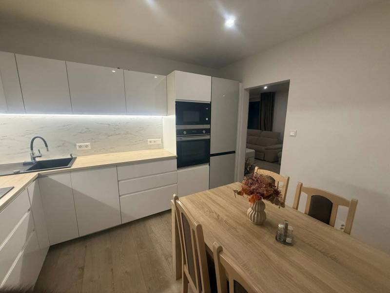 A kitchen in a 3-room apartment with bright lighting and a decorative wooden table.