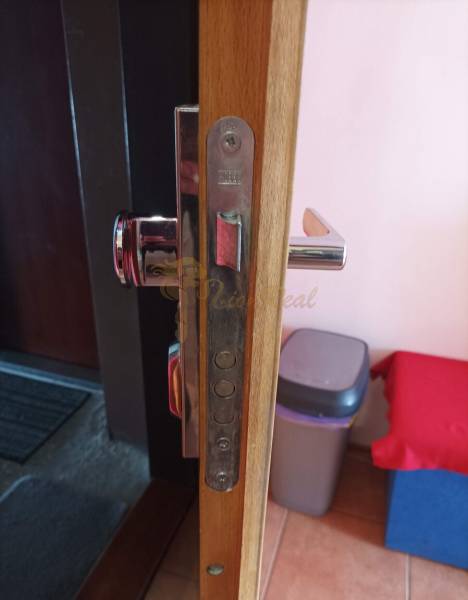 Detail of the door hardware and lock in a one-room apartment with a wooden decor floor.
