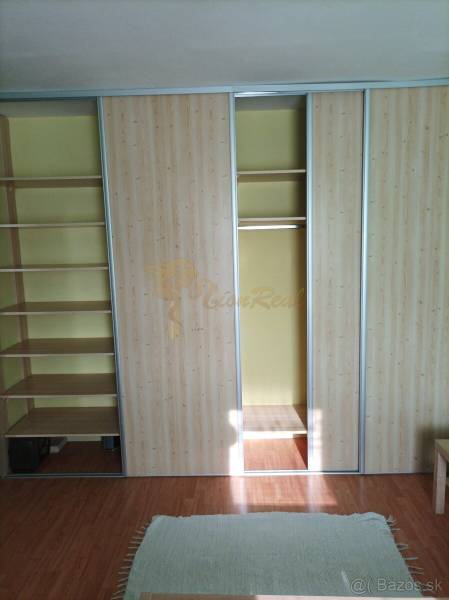 Built-in wardrobe with sliding doors and shelves, floor with wood decor in a studio apartment.