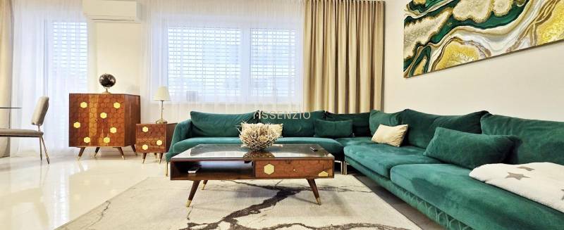 Family house with a green-toned sofa, wooden furniture, and art on the wall.