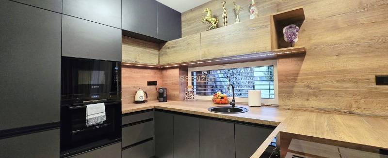 A kitchen in a family house with dark cabinets and a wood-patterned floor.