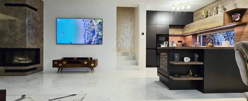 Living room in a family house with a fireplace and a kitchen island, floor with wooden decor.
