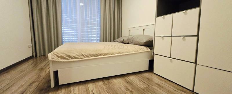 Bedroom in a family house with a bed and a wardrobe, floor with wooden decor.