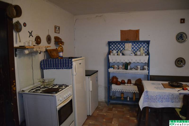 A kitchen in a family house with traditional furniture and decorations, and a wooden-patterned floor.