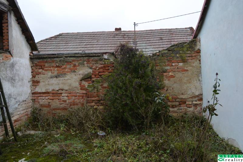 A dilapidated brick wall and a neglected yard of a family house in Abrahám.