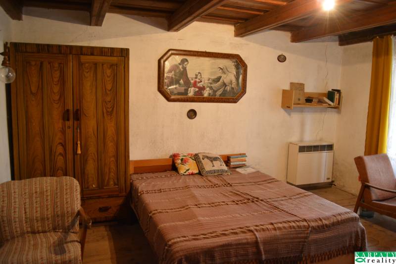 Bedroom in a family house with a wooden wardrobe, bed, and a picture on the wall.
