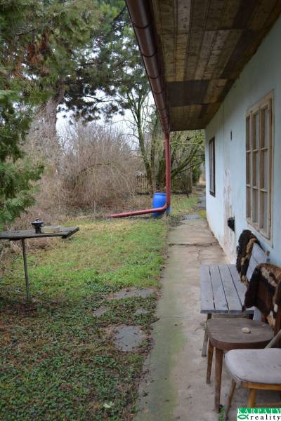 The garden of a family house in Abrahám with a bench, green area, and trees.