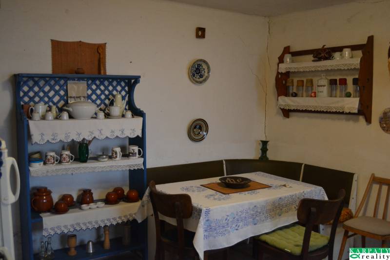 A dining room in a family house with a blue shelf and wooden furniture, decorated with dishes and a tablecloth.