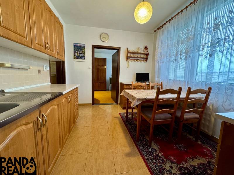 A kitchen in a 3-room apartment with a dining table, floor with wood decor.