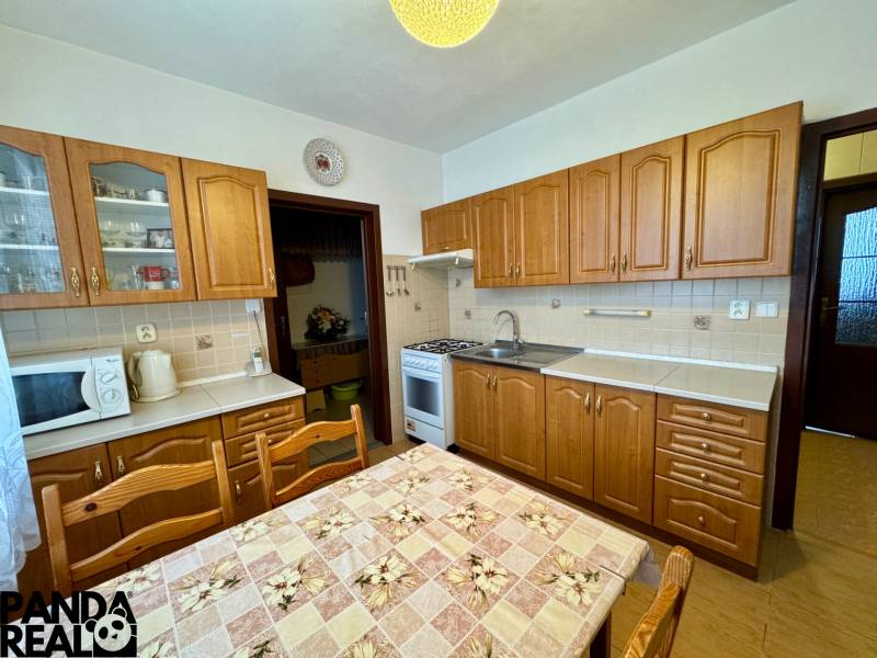 A kitchen with wooden cabinets and a dining table, suitable for a 3-room apartment.