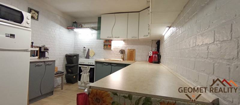 A kitchen in a family house with white brick walls and kitchen appliances.