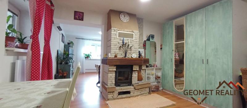 Interior of a family house with a fireplace and a wooden decor floor, complemented by colorful decorations.