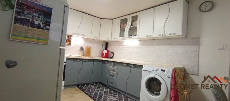 A kitchen in a family house with white and gray cabinets, a floor with a wooden decor.