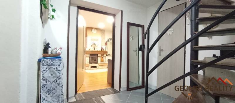 Interior of a family house with a staircase, wood-patterned flooring, and a fireplace.