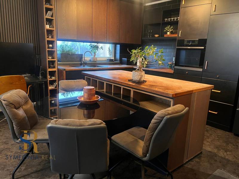 A kitchen in a 2-room apartment with black cabinets and a wood-patterned floor.