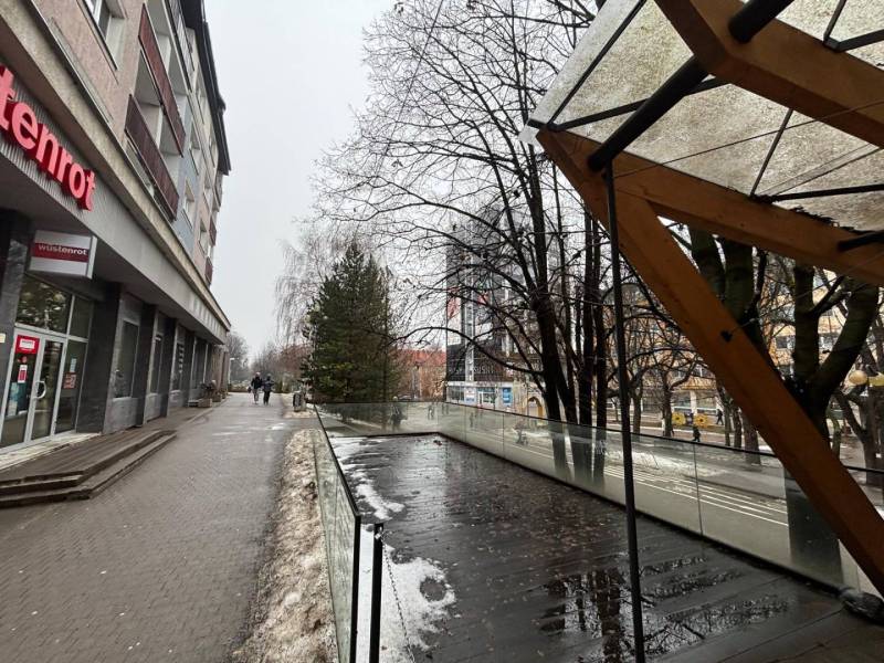 Commercial premises in Poprad next to glass railings and wet tiles, snowy sidewalk.