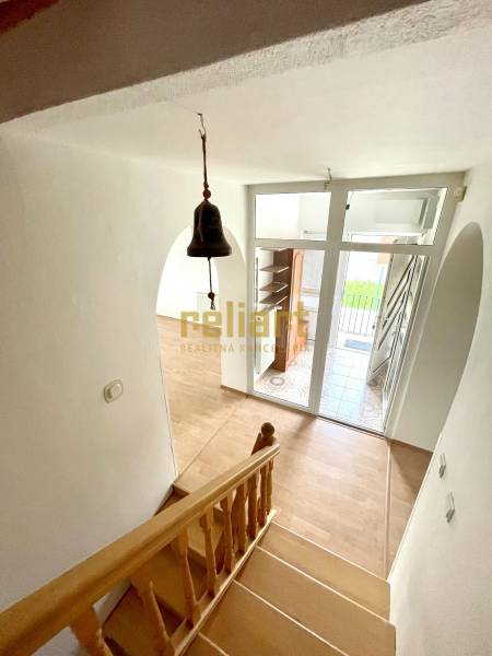 Staircase with a wooden decor floor, entrance door, and doorbell in a family house.