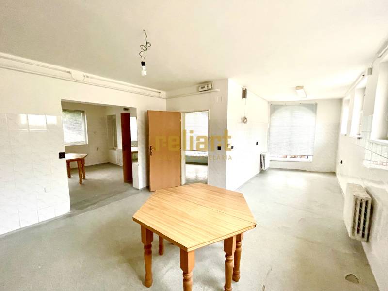 A spacious room with wooden tables and radiators in a family house.
