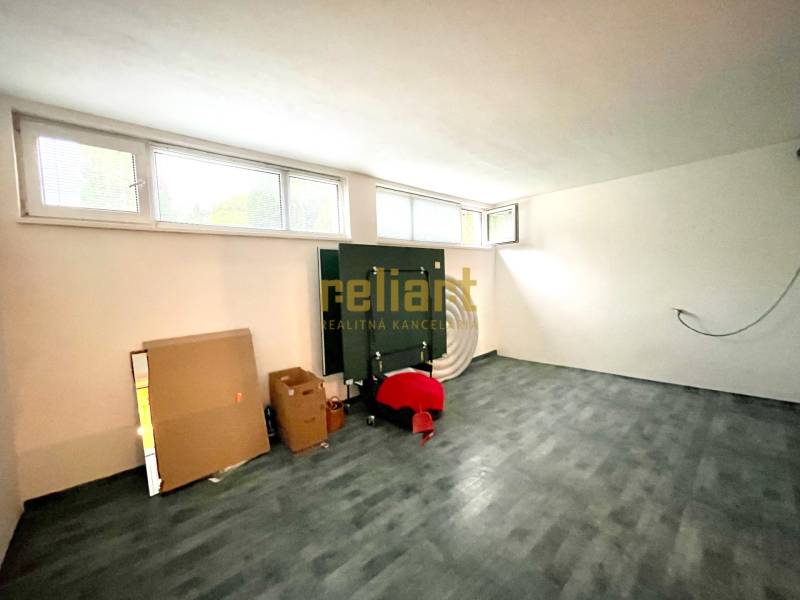 A room in a family house with a wooden decor floor, windows, and cardboard boxes.