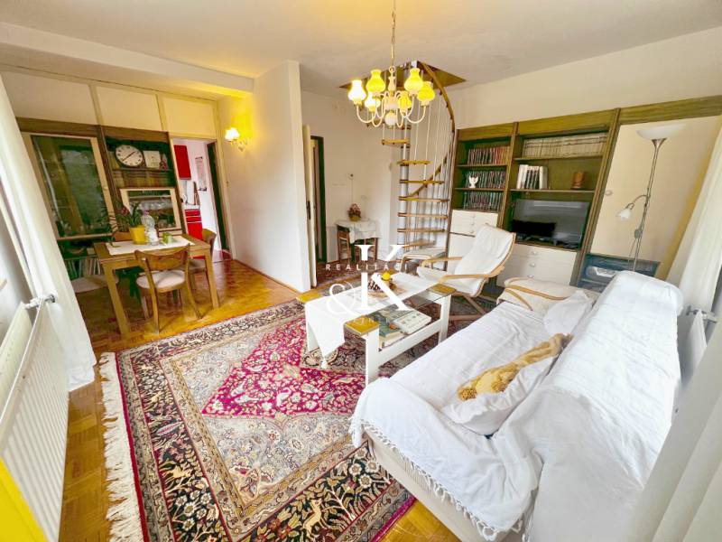 The interior of a cabin with a spiral staircase, a television, and a table on a floor with a wooden decor.