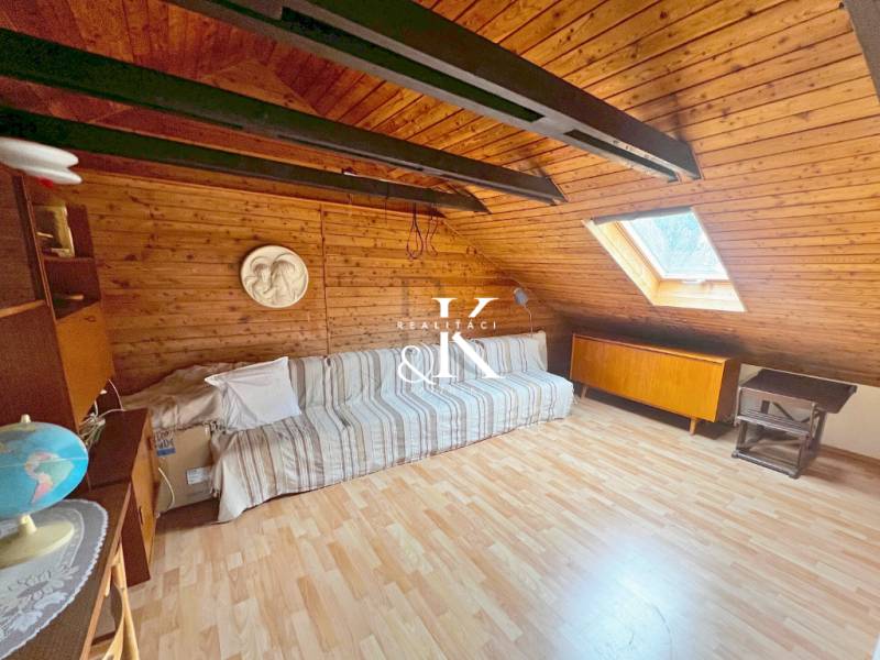 Attic room in a cottage with a wooden decor floor and a skylight.
