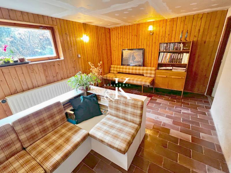 Interior of a cottage with a living room, rustic furniture, and brick flooring.