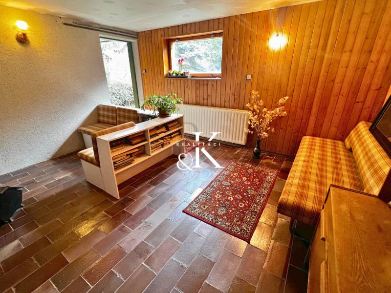 Living area in a cabin with brick flooring and wooden decor on the walls.