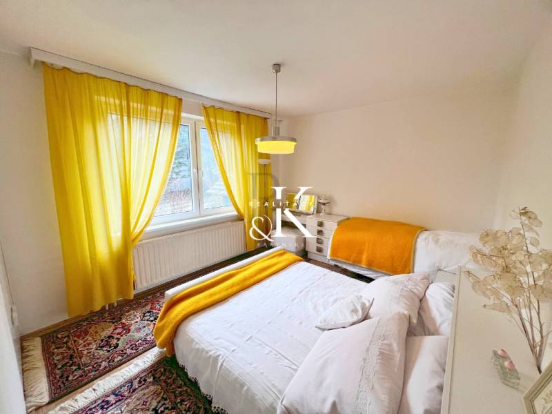 A bright bedroom in a cabin with white walls, yellow curtains, and a carpet.