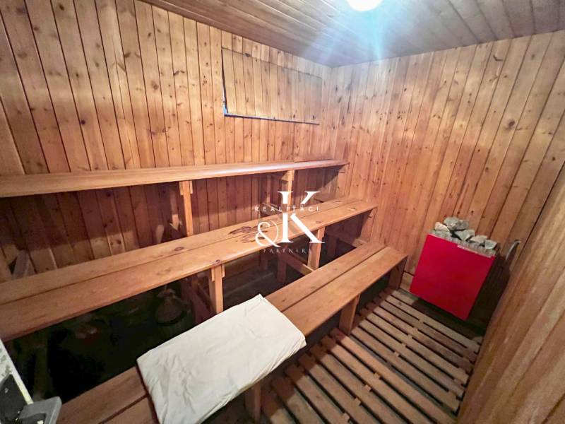 Wooden sauna with benches and a stove in the cabin.