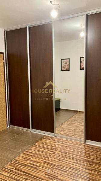 A wardrobe with sliding doors and a mirror in a 3-room apartment with a wood-patterned floor.