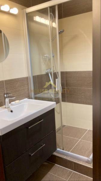 Bathroom with a sink, shower corner, and brown wall tiles in a 3-room apartment.