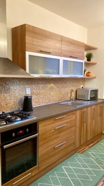 A kitchen with wooden decor and built-in appliances in a 3-room apartment.
