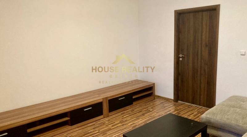 Living room with wood-patterned flooring in a 3-room apartment, light walls, wooden furniture.