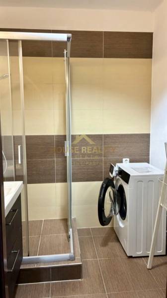 A bathroom with a shower and a washing machine in a 3-room apartment.