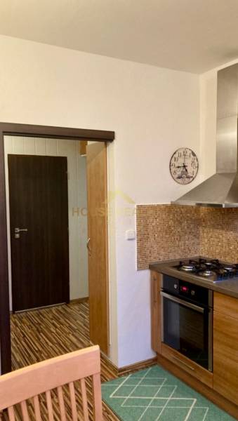 A kitchen in a 3-room apartment with a gas stove, mosaic tiles, and a floor with a wooden decor.
