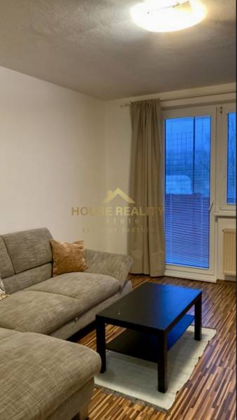 Living room with a sofa, black table, and wood-patterned flooring in a 3-room apartment.