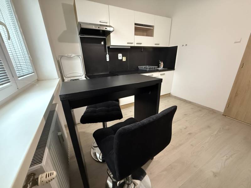 A kitchen with seating and a wooden decor floor in a studio apartment.