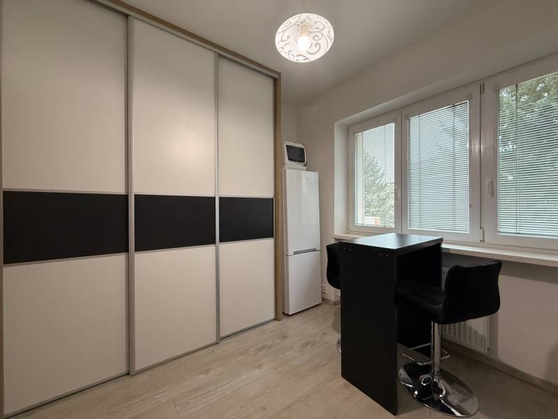 Furnishing of a studio apartment, sliding wardrobe, tall refrigerator, table with two chairs.