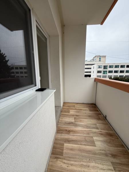A balcony in a one-room apartment with a wooden decor floor.