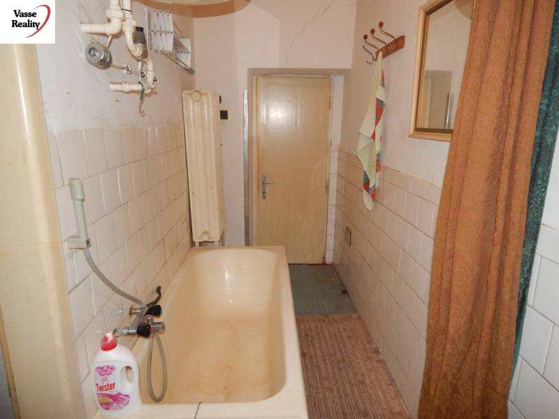 A bathroom in a family house with an older bathtub and tiles on the walls.
