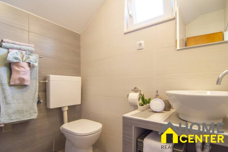 Bathroom in a holiday apartment with a shower, sink, toilet, and small decorations.