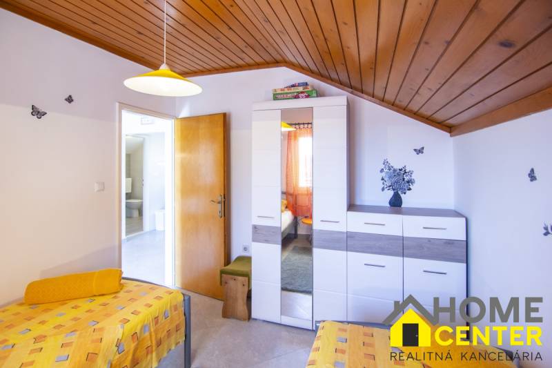 Bedroom in a Holiday Apartment with colorful bedding, a cabinet, and wall decorations.