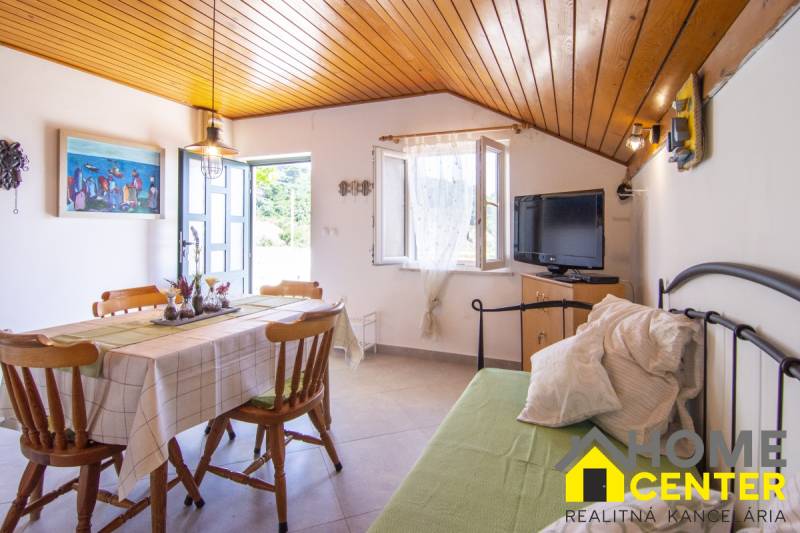 Recreational apartment with a dining area, television, open window, and wooden ceiling.