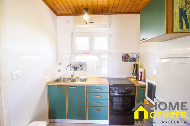 The kitchen in the holiday apartment with green cabinets, a stove, and decorative tiles.
