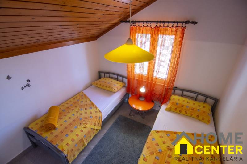 Double room in a holiday apartment with colorful textiles and wooden ceiling paneling.