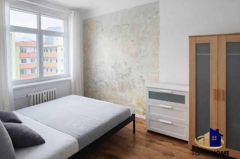 A bedroom in a 2-room apartment with wooden decor and an original wall.